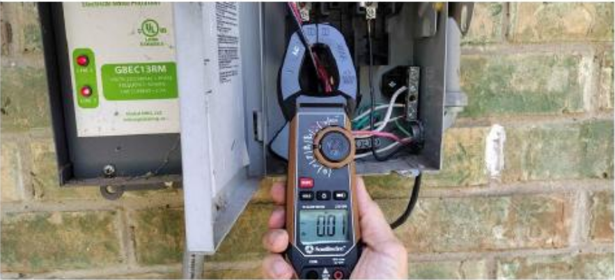 House Fluent inspector testing solar electrical equipment with a clamp meter at a residential panel